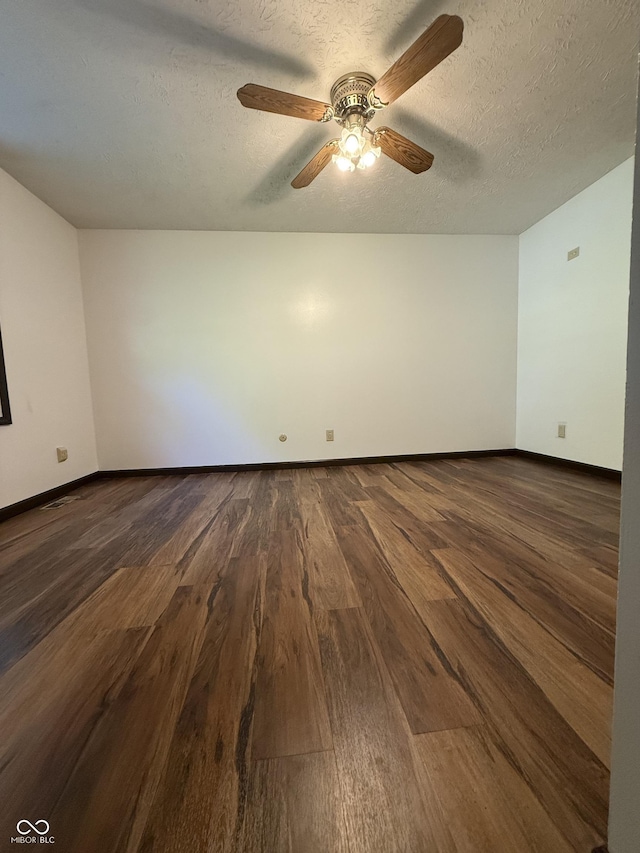 spare room with dark wood-style flooring, a ceiling fan, baseboards, and a textured ceiling