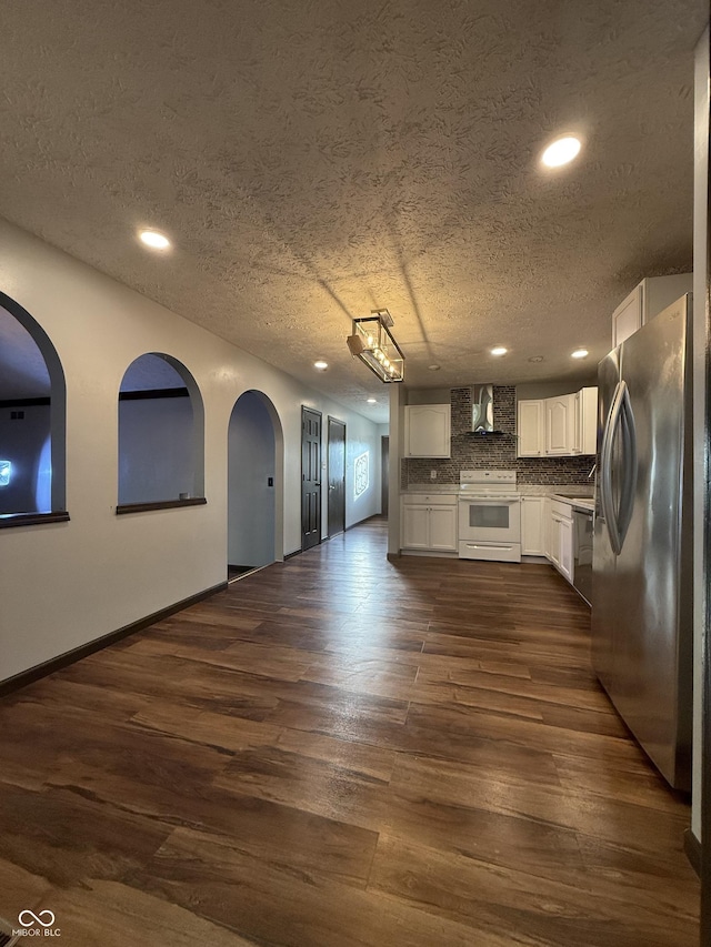 kitchen with freestanding refrigerator, white electric range, wall chimney range hood, recessed lighting, and dark wood-style flooring