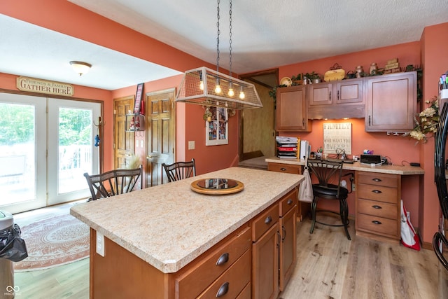 455 E Main St, Danville, IN 46122 - kitchen with light wood finished floors, light countertops, brown cabinetry, a center island, and pendant lighting