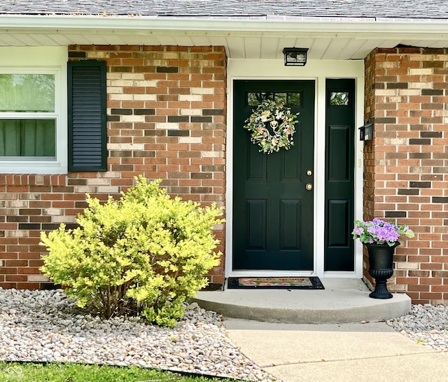 entrance to property with brick siding and roof with shingles
