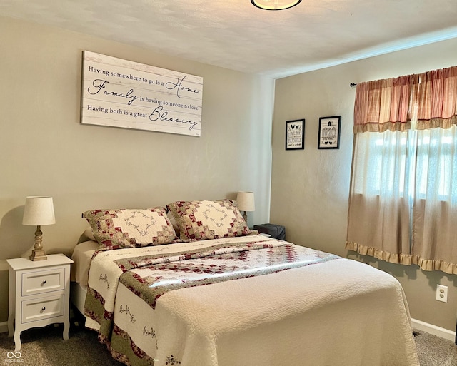bedroom featuring dark colored carpet and baseboards