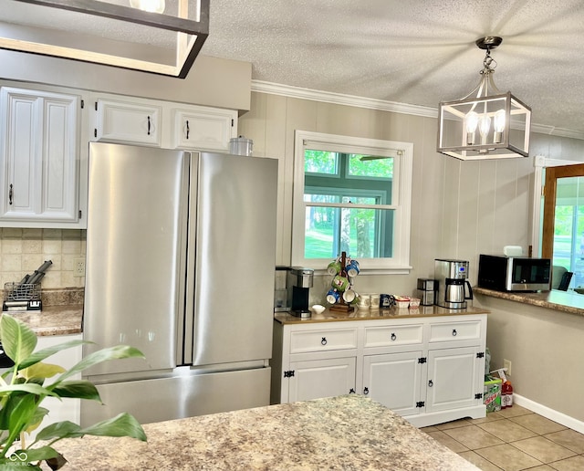 kitchen with stainless steel appliances, crown molding, backsplash, white cabinetry, and a chandelier