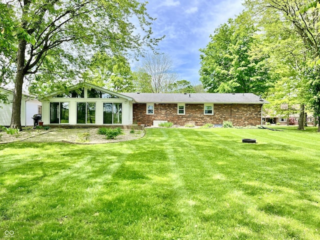 back of property featuring a yard and brick siding