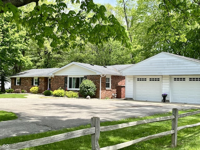 single story home with a garage, fence, driveway, and brick siding