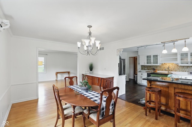 6825 Farmleigh Dr, Indianapolis, IN 46220 - dining room featuring rail lighting, a chandelier, light wood-style floors, and crown molding
