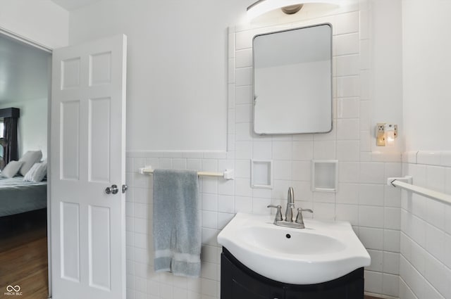 6825 Farmleigh Dr, Indianapolis, IN 46220 - bathroom with tile walls, connected bathroom, vanity, a wainscoted wall, and wood finished floors
