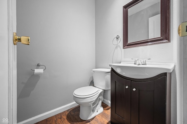 bathroom featuring vanity, toilet, baseboards, and wood finished floors