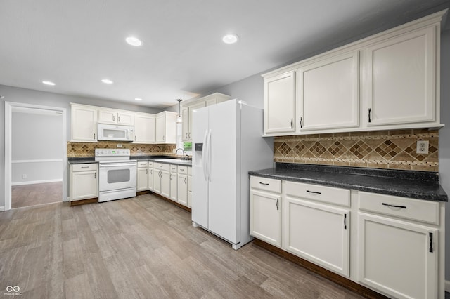 kitchen featuring white appliances, a sink, backsplash, light wood-type flooring, and dark countertops