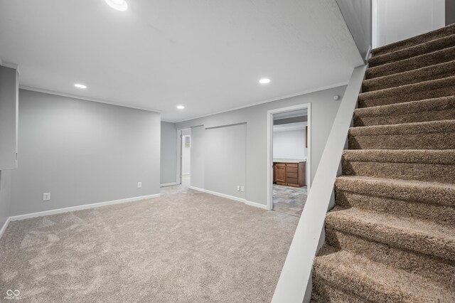 finished below grade area featuring recessed lighting, stairs, carpet floors, baseboards, and crown molding