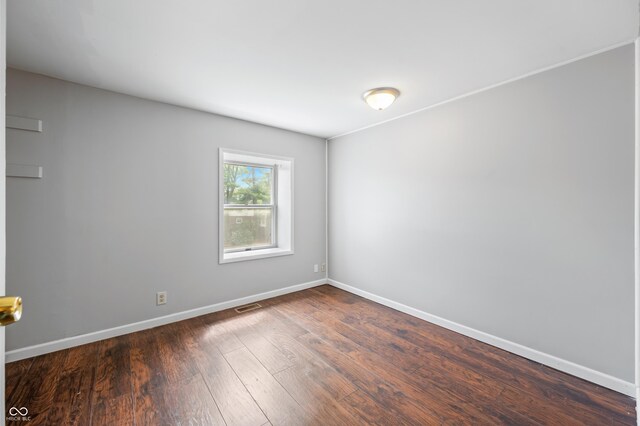 spare room with dark wood-type flooring and baseboards