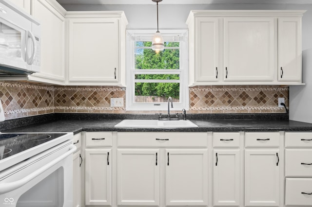 kitchen with white appliances, a sink, white cabinetry, and dark countertops