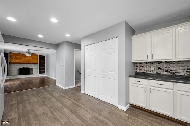 kitchen featuring baseboards, dark wood finished floors, dark countertops, and recessed lighting