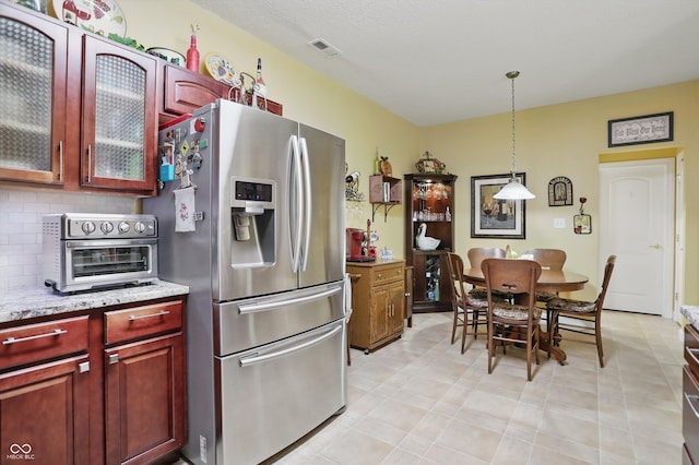 1663 Sweetgum Dr, Greenwood, IN 46143 - kitchen with stainless steel fridge, reddish brown cabinets, decorative light fixtures, backsplash, and glass insert cabinets