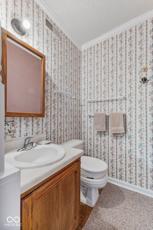 half bathroom featuring vanity, ornamental molding, toilet, and a textured ceiling