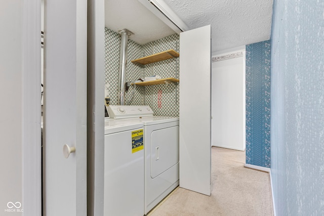 laundry room featuring light carpet, separate washer and dryer, and a textured ceiling