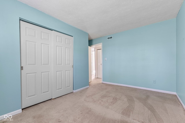 unfurnished bedroom with carpet, baseboards, a closet, and a textured ceiling