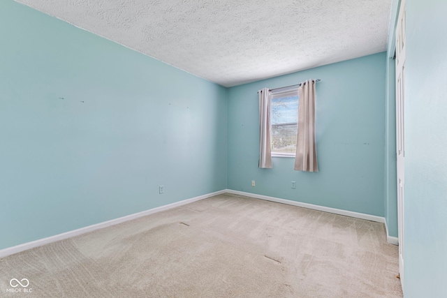 carpeted spare room featuring baseboards and a textured ceiling