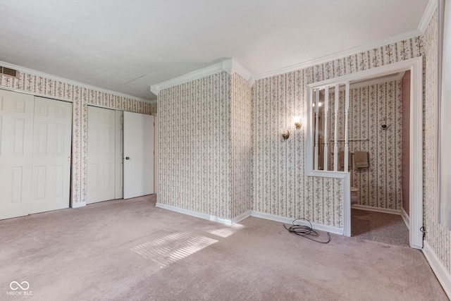 unfurnished bedroom featuring ornamental molding, multiple closets, wallpapered walls, and carpet