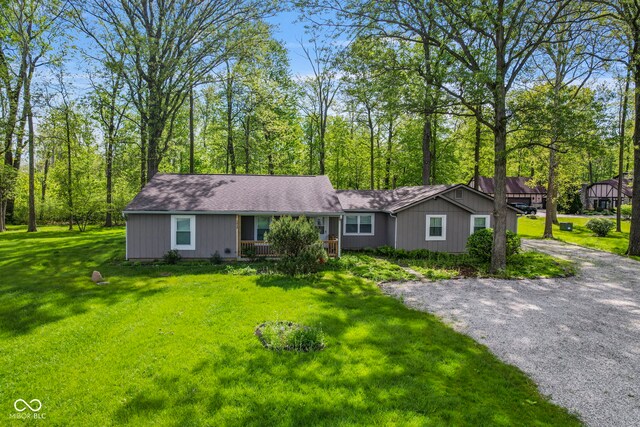 ranch-style home featuring a front yard, a shingled roof, and gravel driveway