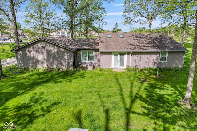 view of front facade with a front yard, roof with shingles, and french doors