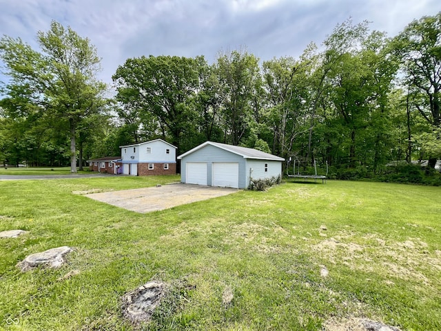 206 Windemere Rd, West Terre Haute, IN 47885 - view of grassy yard featuring a trampoline, a garage, and an outbuilding