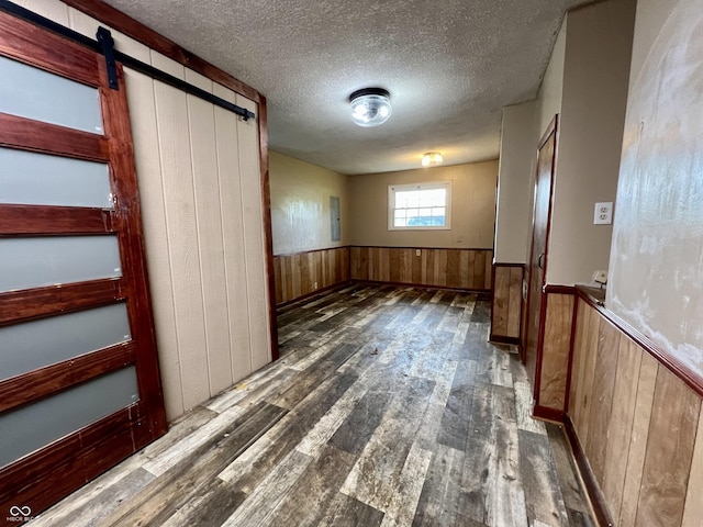 206 Windemere Rd, West Terre Haute, IN 47885 - empty room featuring wood finished floors, wood walls, wainscoting, a textured ceiling, and a barn door