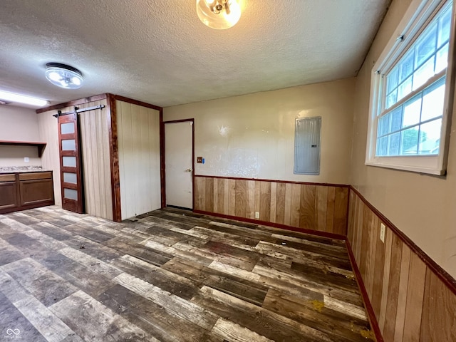 206 Windemere Rd, West Terre Haute, IN 47885 - empty room with a barn door, wood-type flooring, a textured ceiling, electric panel, and wood walls