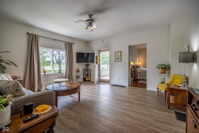 living area with a ceiling fan, wood finished floors, and baseboards