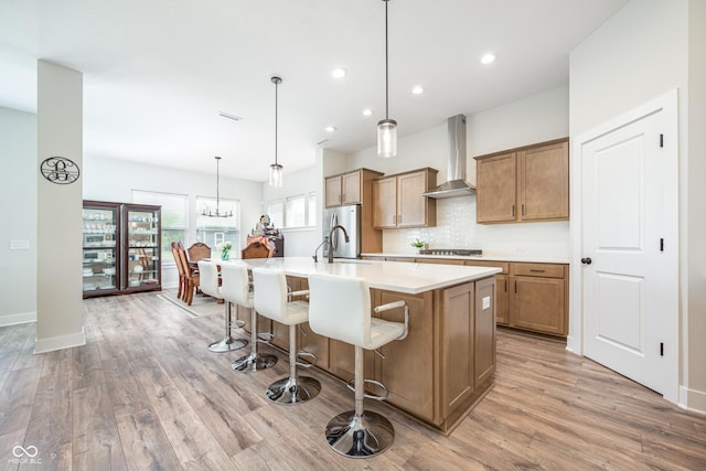 15792 Wiseman Dr, Fishers, IN 46040 - kitchen with wall chimney range hood, stainless steel appliances, light wood-type flooring, an island with sink, and recessed lighting
