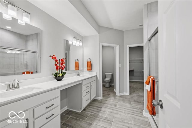bathroom featuring a shower stall, toilet, double vanity, and baseboards