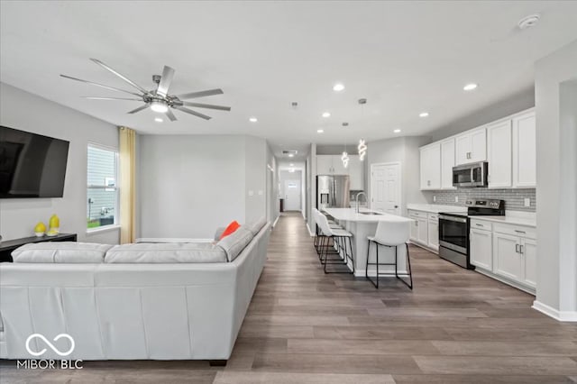 living area featuring a ceiling fan, recessed lighting, and wood finished floors