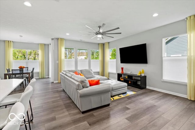 living area featuring plenty of natural light, ceiling fan, baseboards, wood finished floors, and recessed lighting
