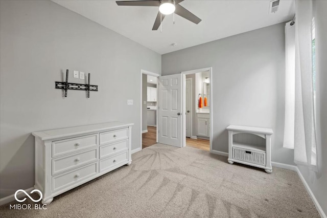 carpeted bedroom featuring baseboards, ensuite bathroom, and a ceiling fan