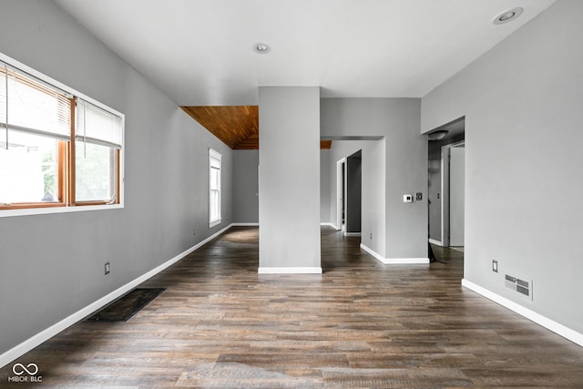 empty room featuring wood finished floors, baseboards, and vaulted ceiling