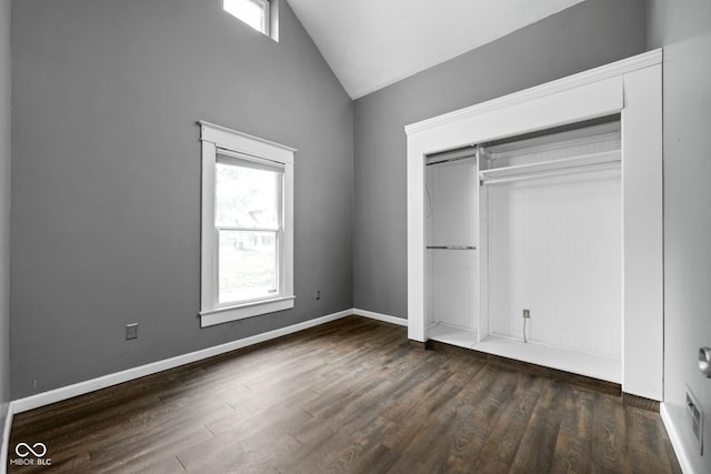 unfurnished bedroom featuring dark wood-style floors, a closet, high vaulted ceiling, and baseboards
