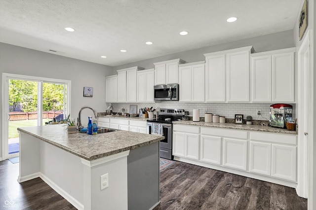 4032 Stubbington Ln, Indianapolis, IN 46239 - kitchen featuring appliances with stainless steel finishes, a sink, dark wood-style flooring, tasteful backsplash, and a center island with sink