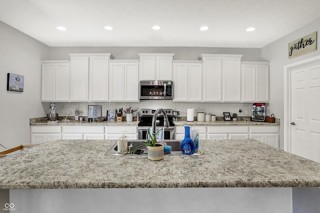 4032 Stubbington Ln, Indianapolis, IN 46239 - kitchen with appliances with stainless steel finishes, a sink, white cabinetry, tasteful backsplash, and recessed lighting