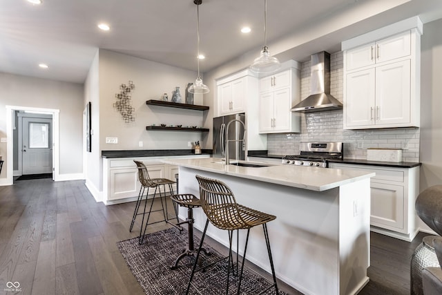 kitchen with wall chimney exhaust hood, appliances with stainless steel finishes, open shelves, a sink, and backsplash