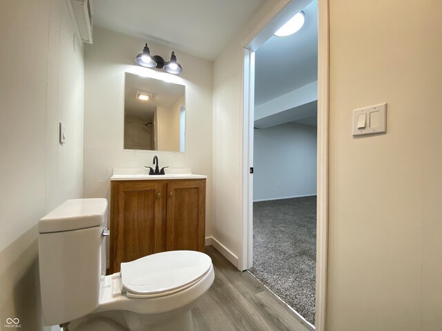 bathroom featuring toilet, wood finished floors, vanity, and baseboards