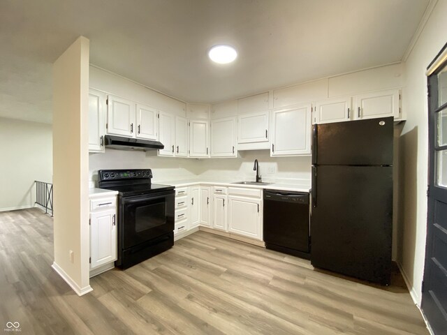 kitchen with black appliances, a sink, under cabinet range hood, light countertops, and light wood finished floors
