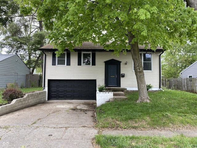 raised ranch with fence, an attached garage, and concrete driveway