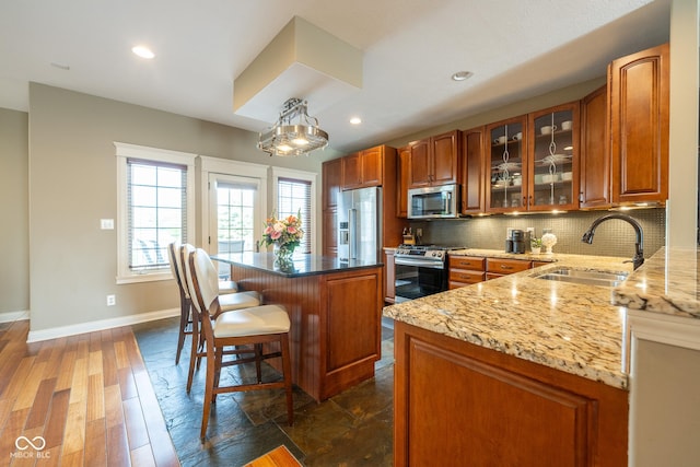 4890 Benthaven Dr E, Bargersville, IN 46106 - kitchen with stainless steel appliances, a sink, backsplash, a breakfast bar area, and baseboards