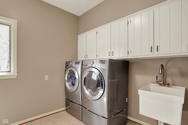 laundry area featuring separate washer and dryer, cabinet space, baseboards, and light tile patterned floors
