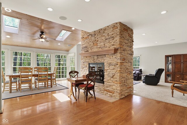 living area featuring a skylight, wood finished floors, recessed lighting, lofted ceiling, and a stone fireplace