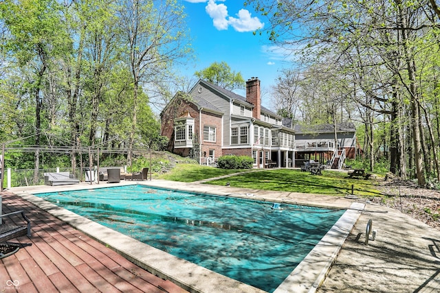 view of pool with a covered pool, a wooden deck, a yard, and a patio