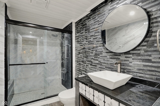 bathroom featuring toilet, tile walls, a stall shower, vanity, and decorative backsplash