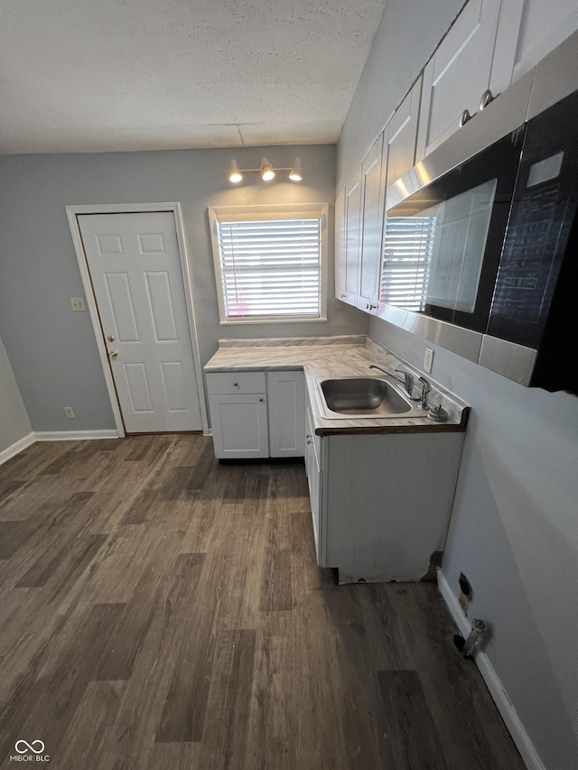 2037 Glenridge Dr, Indianapolis, IN 46218 - kitchen with a sink, dark wood-type flooring, light countertops, white cabinetry, and a textured ceiling
