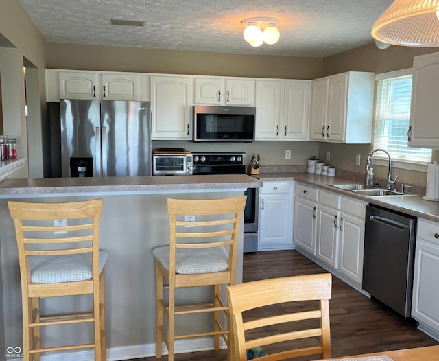 14058 Southwood Cir, Fishers, IN 46037 - kitchen with appliances with stainless steel finishes, a sink, white cabinets, a kitchen bar, and dark wood-type flooring