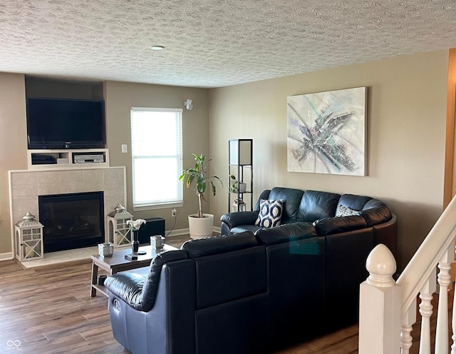 14058 Southwood Cir, Fishers, IN 46037 - living area with wood finished floors, a textured ceiling, a fireplace, baseboards, and stairway