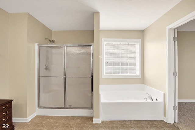 bathroom featuring a stall shower, a bath, and baseboards